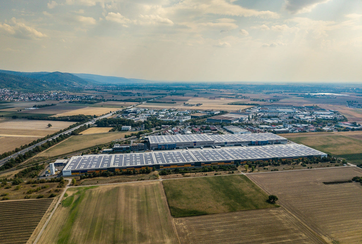 Luftaufnahme eines Gewerbegebiets mit großen Hallen und Photovoltaik auf den Dächern