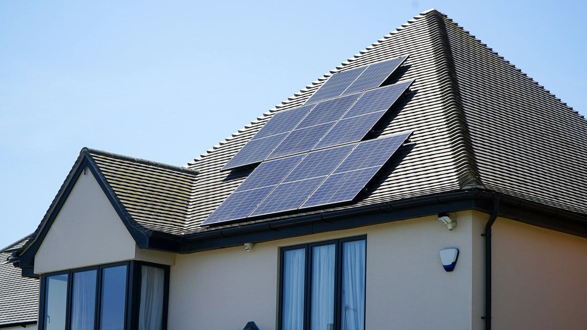 Einfamilienhaus mit Photovoltaikmodulen auf dem Walmdach vor blauem Himmel