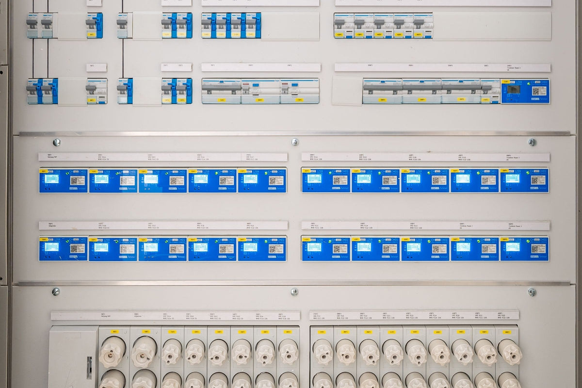 Zählerfeld mit zwei Reihen digitaler Stromzähler und Leitungsschutzschaltern in einem modernen Verteilerschrank